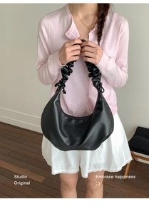 Detail shot of a black crescent shoulder bag with scrunchie style handle on a model