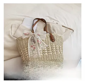Detail of straw tote bag with brown leather handles and pink rose floral lace bow