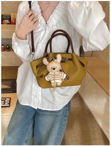 Detail of mustard yellow lychee pattern bag with brown leather handles and bear charm