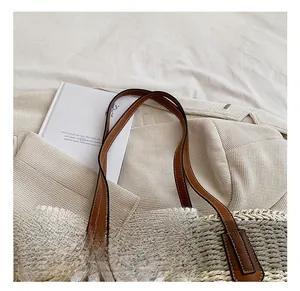 Detail of straw woven tote bag featuring floral lace bow and brown leather handles