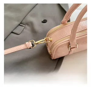 Close-up of pink glossy handbag with gold metal hooks and dual zipper details