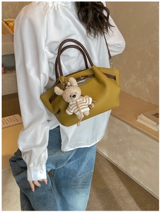 Detailed macro view of mustard yellow leather handbag with silver lock and bear charm