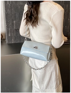 Détail du sac d'épaule en cuir verni bleu clair avec chaîne argentée sur modèle