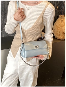 Détail du sac bandoulière bleu clair avec fermoir argenté et chaîne sur mannequin