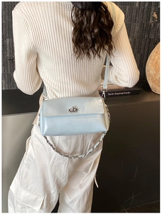 Détail du sac bandoulière bleu clair avec fermoir rotatif argenté et chaîne décorative