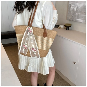 Detail of woven straw tote bag with elegant lace ribbons and floral embroidery accents