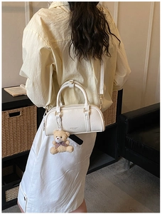 Detail of a creamy Boston bag with wrinkled leather texture and cute bear charm pendant