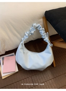 Detail of light blue crescent bag with scrunchie handle on dark wooden floor