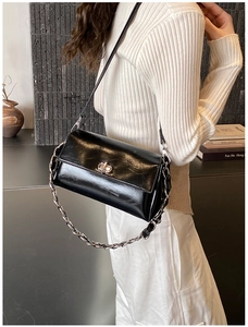 Détail d'un sac bandoulière en cuir brillant noir avec fermoir doré et chaîne en métal