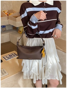 Détail du sac bandoulière en cuir marron avec logo doré et charm cheval jaune