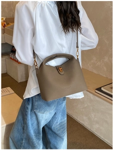 Litchi pattern leather bucket bag in taupe with gold hardware worn by a model