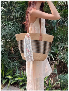 Close-up of woven straw tote featuring black stripes, leather handles and floral lace scarf