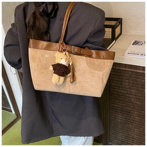 Detail view of large tote bag with brown leather patchwork and cute bear charm pendant
