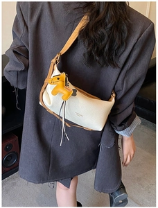 Détail du sac bandoulière crème avec sangle marron et accessoire de charme de cheval