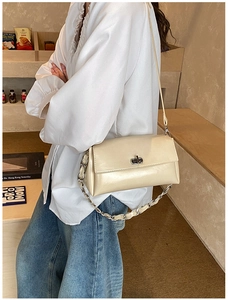 Détail du sac bandoulière en cuir crème avec fermoir rotatif argenté et chaîne métallique