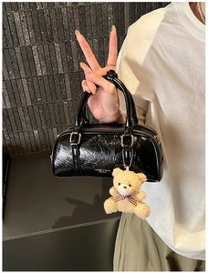 Détail du sac Boston en cuir verni noir avec texture plissée et charmant ours peluche