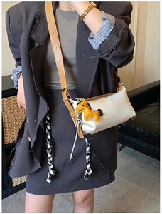 Détail du sac bandoulière crème avec bordure marron et breloque poney jaune