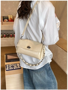 Détail du sac beige avec fermoir rotatif en métal et chaîne décorative élégante