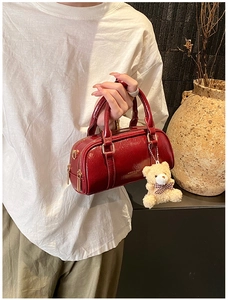 Detail of red Boston leather handbag with dual zippers and a cute teddy bear pendant