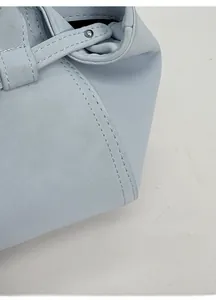 Détail des coutures fines et du rivet argenté sur le sac seau en cuir bleu clair
