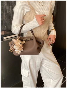 Detail of vintage brown leather handbag featuring a metal twist lock and a cute rabbit charm