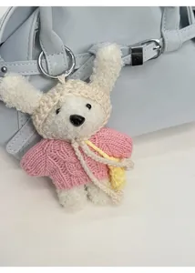 Gros plan d'un lapin au crochet fait main avec pull rose sur un sac à main bleu