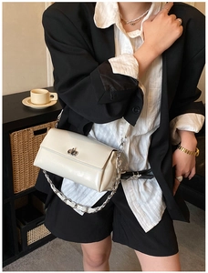 Détail d'un chic sac bandoulière en cuir verni crème avec chaîne argentée et fermoir