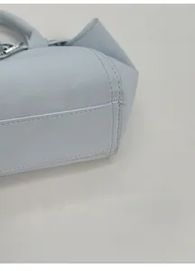 Détail macro de la base élargie et des coutures fines sur le sac à main en cuir bleu clair