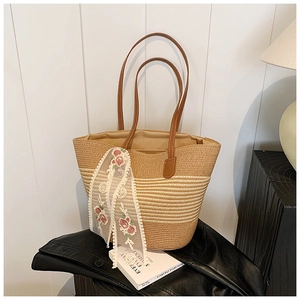 Detail of straw tote bag featuring white lace flower ribbon and brown leather handles