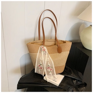 Detail of straw woven tote bag featuring rose embroidery lace ribbons and brown handles