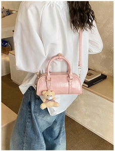 Détail du sac Boston rose avec texture gaufrée brillante et breloque ours en peluche