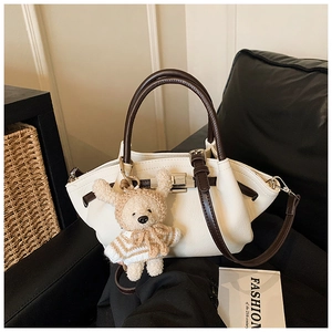 Detail of vintage cream handbag with dark brown handles and cute teddy bear charm accessory