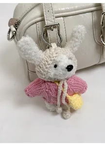 Detail of crochet puppy charm with pink sweater on a white leather boston handbag