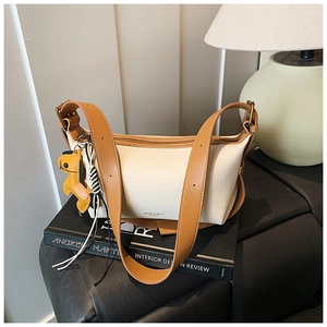 Détail du sac bandoulière bicolore en cuir avec breloque chien jaune et large bandoulière
