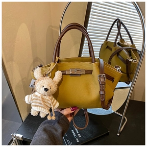 Mustard yellow pebbled leather handbag with brown handles and a cute bear charm detail