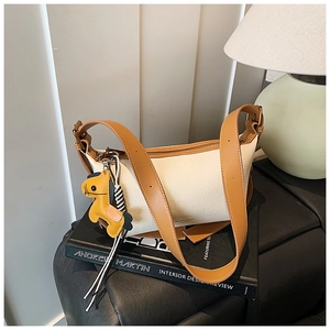 Détail du sac bandoulière en cuir grainé crème avec sangle marron et breloque cheval