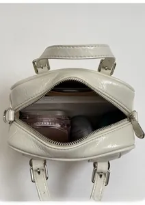 Interior view of off-white patent leather bag showing space for phone and makeup