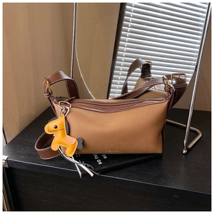 Détail du sac bandoulière bicolore marron avec texture litchi et breloque cheval