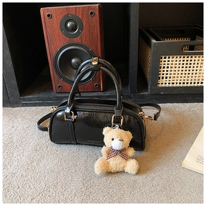 Vue détaillée d'un sac Boston noir brillant avec texture plissée et peluche ours