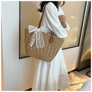 Detail of hand-woven straw tote bag with floral lace bow and premium leather handles