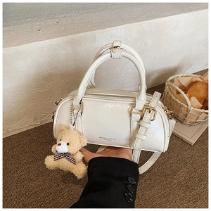 Détail du sac Boston en cuir plissé blanc avec bijoux dorés et breloque ours doux