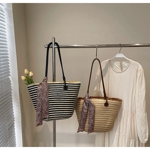 Close-up of woven straw tote bags with striped patterns and silk scarf handle details