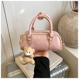 Détail d'un sac Boston rose avec texture en cuir plissé vintage et un joli pendentif d'ours