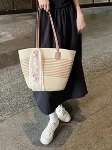 Straw tote bag with brown leather handles and pink floral lace ribbon for beach vacation