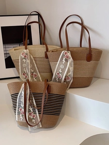 Three large woven straw tote bags with leather handles and lace floral scarves on display