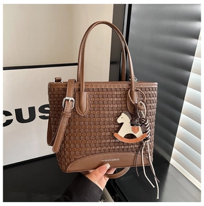 Dettaglio della borsa tote in pelle intrecciata con doppi manici e ciondolo pony