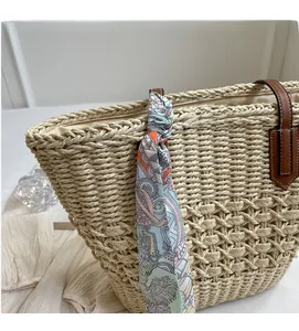 Detail of straw woven tote bag handle with colorful printed silk scarf and leather trim
