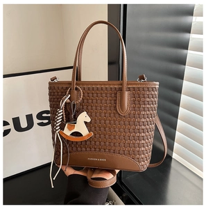 Dettaglio della borsa tote marrone intrecciata con ciondolo a cavallo e logo