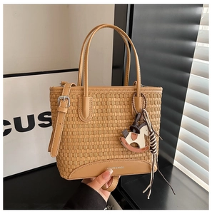 Dettaglio della trama intrecciata della borsa tote color cuoio con ciondolo