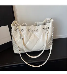 Detail of cream quilted tote bag with silver chain strap and smooth leather texture